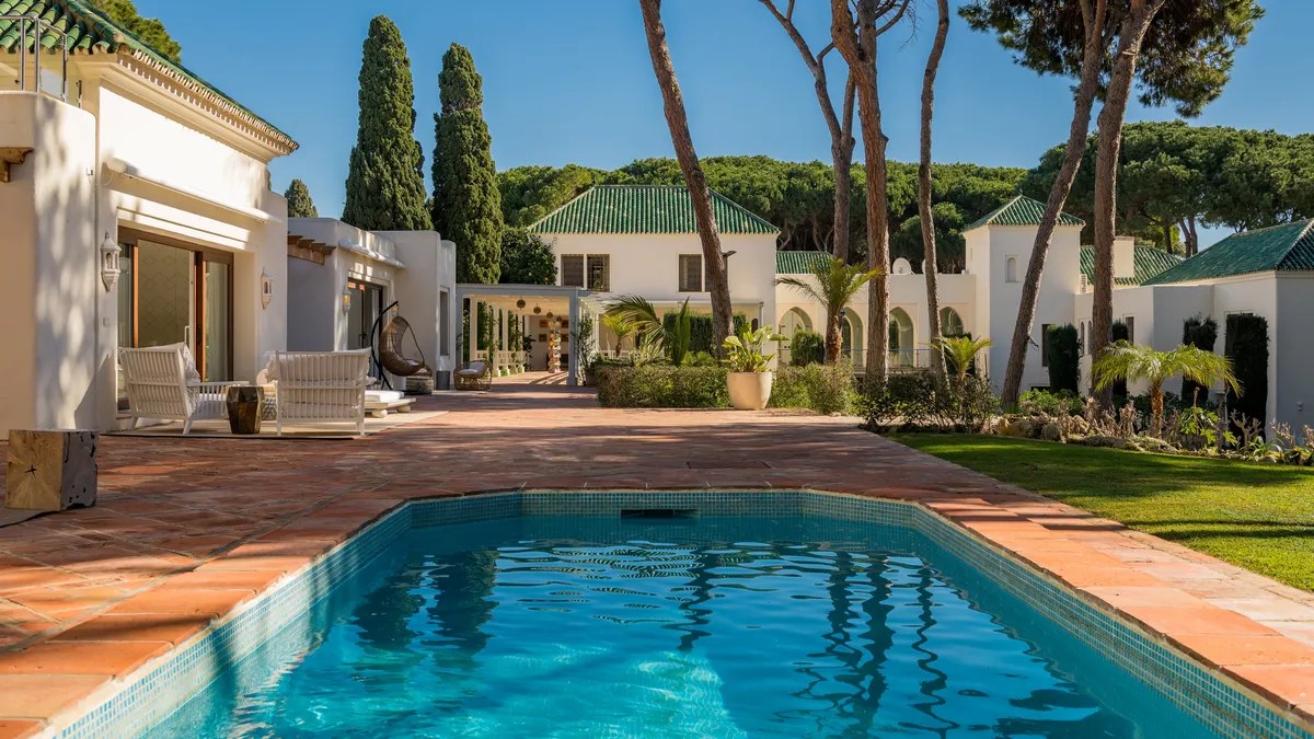 Main pool terrace with loungers facing the white villa and pine trees — Villa El Rincon, Golden Mile