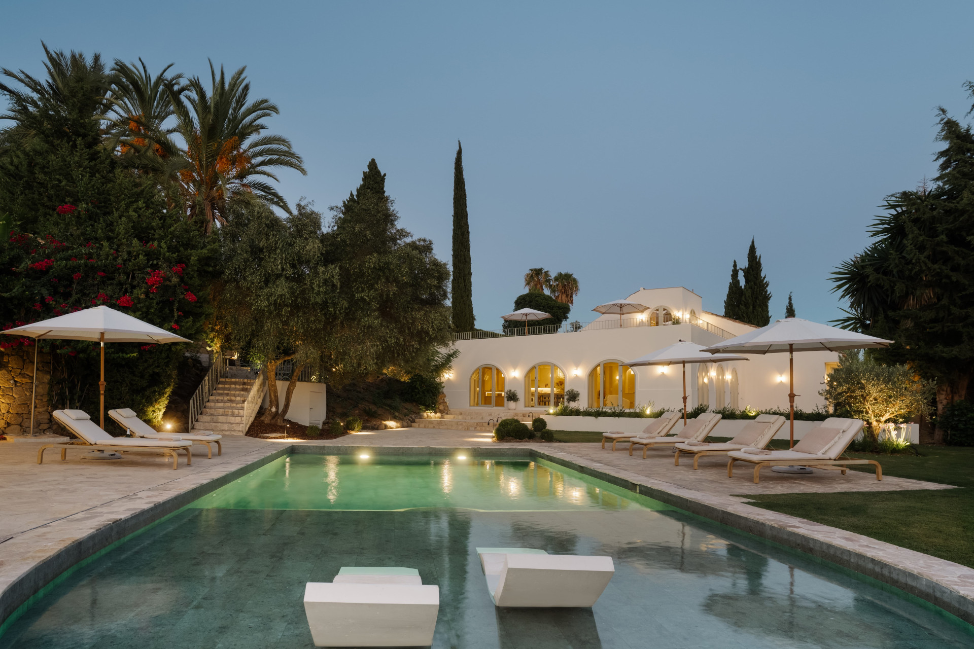 Saltwater pool and Mediterranean villa illuminated at dusk — Blanch House, Nueva Andalucía